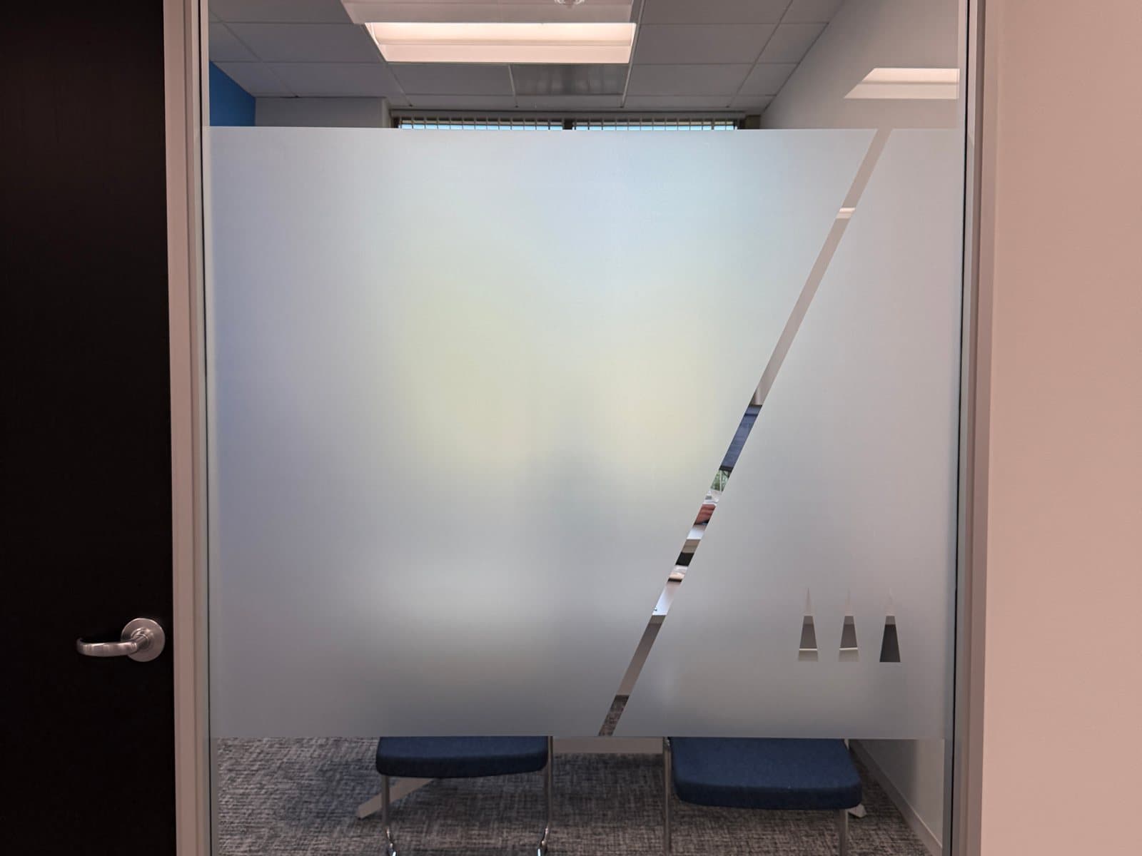 Office front with a frosted band, a clear diagonal stripe and the TGR three-triangle mark cut out of the film