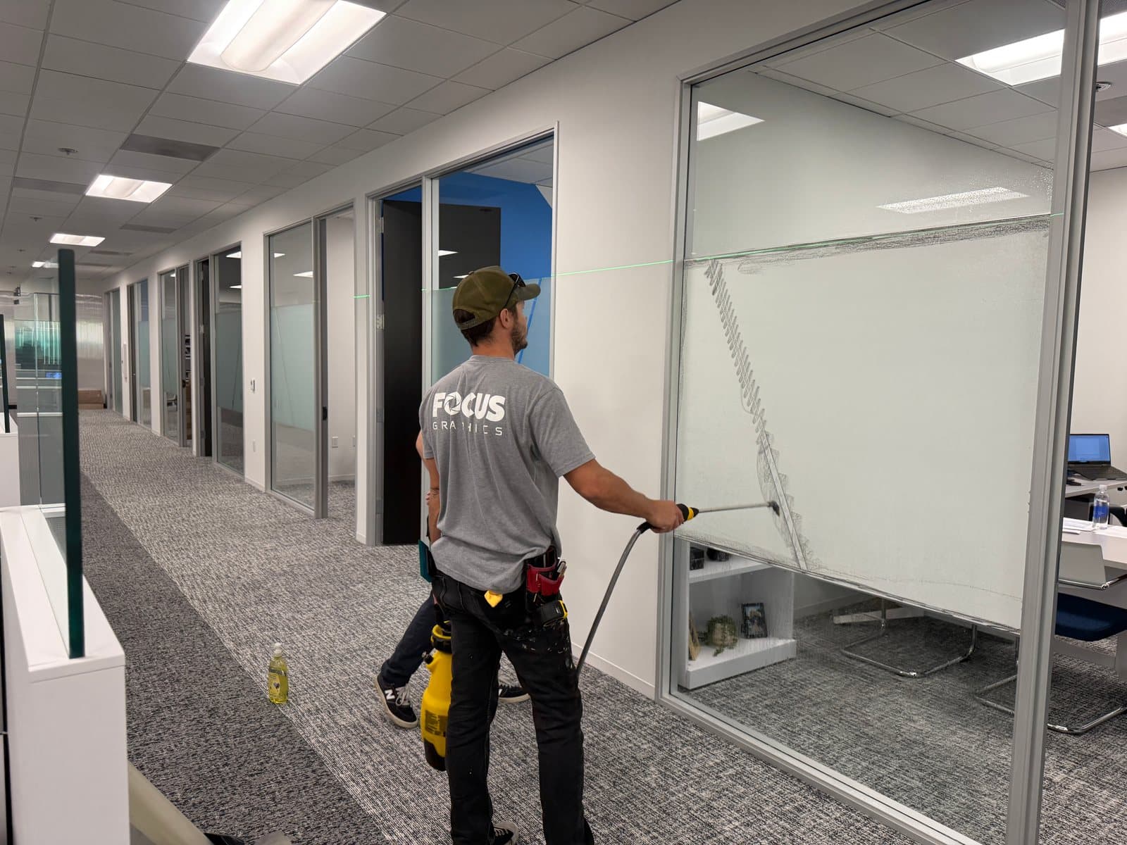Focus Graphics installer spraying a glass office front while applying frosted film