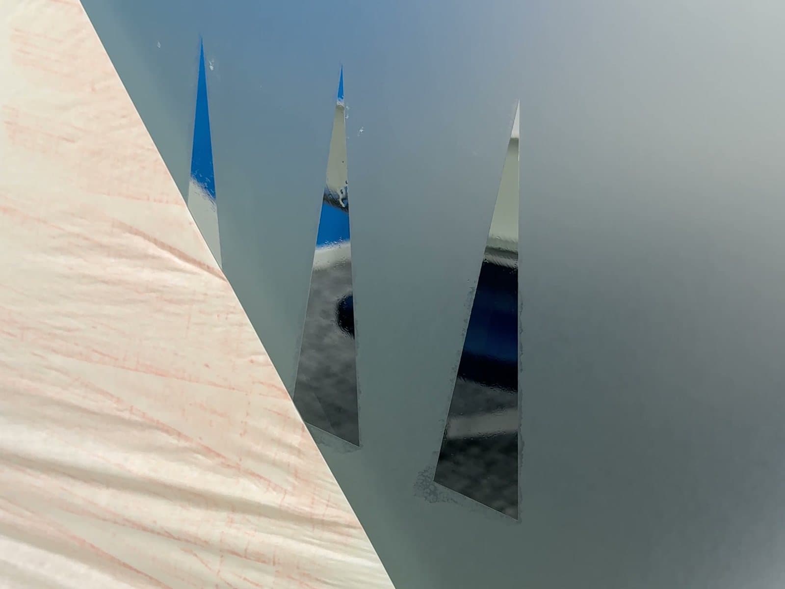 Application tape peeling back off new frosted film to reveal the three cut-out triangles of the TGR mark
